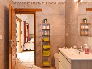 A bathroom with a sink, mirror, and shelves with towels.