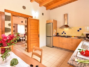 A kitchen with wooden cabinets, a stainless steel refrigerator, and a tiled backsplash.