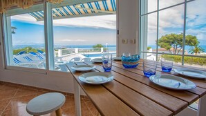 A dining area with a view of the sea, a wooden table, and blue glassware. - The Deck - Luxury Peniscola holiday villa, private pool, wifi,air conditioning (Peniscola)