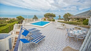 A rooftop pool area with blue lounge chairs, a dining table with chairs, and a view of the sea. - The Deck - Luxury Peniscola holiday villa, private pool, wifi,air conditioning (Peniscola)