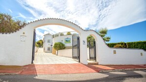 A gated entrance with a white wall, a red pathway, and a clear sky. - The Deck - Luxury Peniscola holiday villa, private pool, wifi,air conditioning (Peniscola)