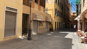 Una stretta via con negozi chiusi e un caffè con tavolini all'aperto.