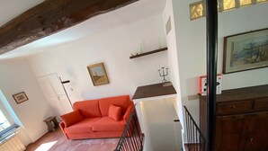 Un soggiorno con un divano rosso, una scala e un quadro appeso al muro.