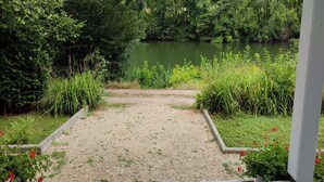 A gravel pathway leading to a body of water, surrounded by lush greenery and a concrete structure.