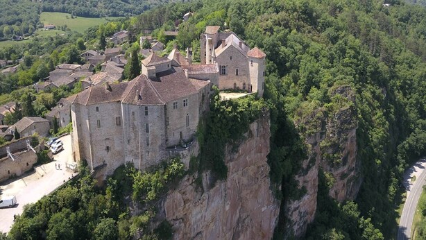A medieval castle perched on a cliff overlooking a valley.