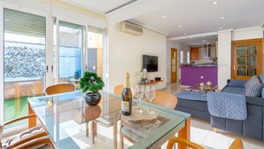 A modern living room with a glass dining table, a sofa, and a kitchen in the background. - Beautiful penthouse in the heart of Alicante (Alacant)