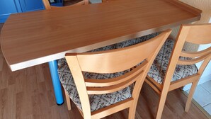 Uma mesa de jantar de madeira com cadeiras combinando, uma perna de cadeira azul e uma almofada estampada.