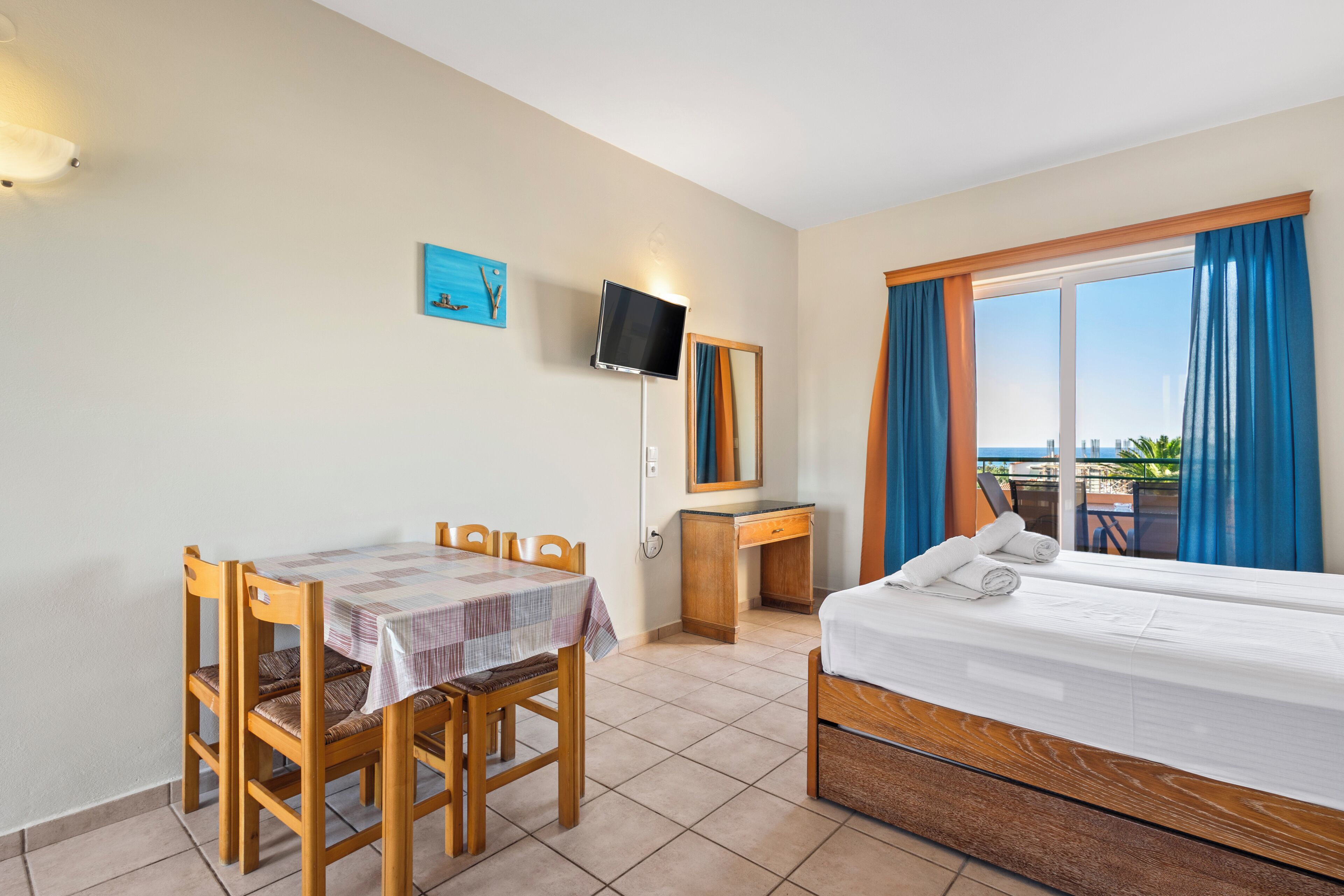 A hotel room with a bed, a desk, a chair, a television, and a window with curtains.