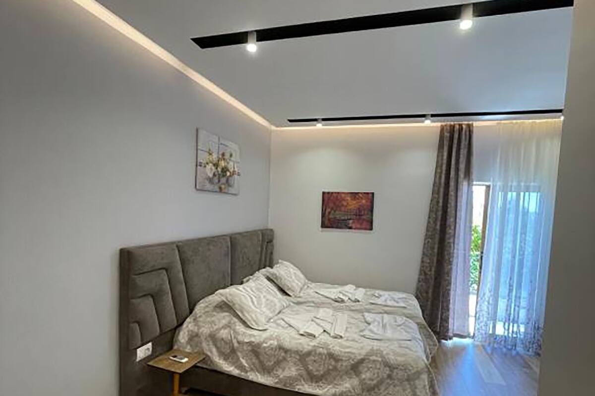 Ein modernes Schlafzimmer mit einem großen Bett, Holzboden und einer Deckenleuchte.