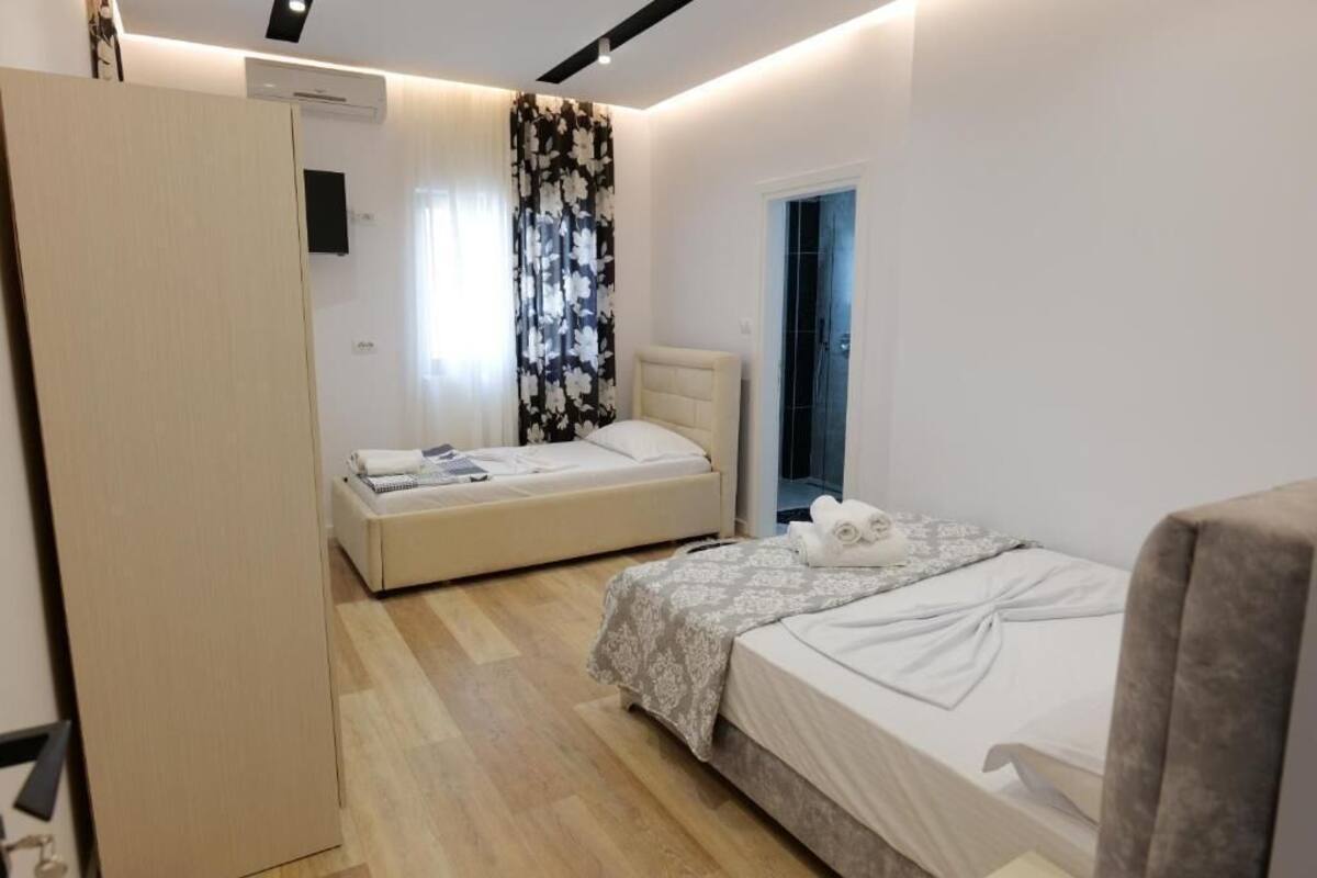 Ein modernes Schlafzimmer mit zwei Betten, einem Kleiderschrank und einem durchgegangenen Tür angedeuteten Badezimmer.