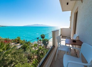 A balcony with a view of the sea, white chairs, and a small table. - Blue Bay Hotel (Sarandë)