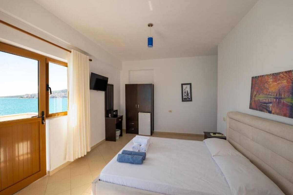 Ein Hotelzimmer mit Bett, Fernseher, Schreibtisch und Meerblick.