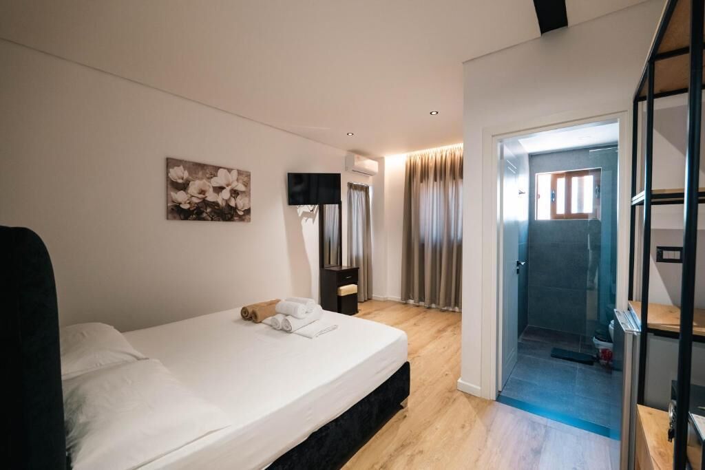 A modern bedroom with a bed, a flat-screen TV, and a painting on the wall.