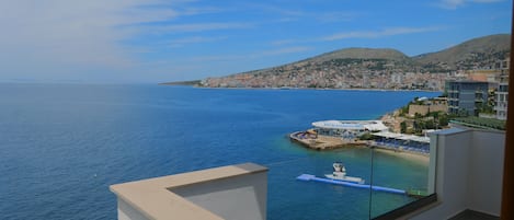 Un paisaje urbano costero con vista despejada al mar, una pequeña embarcación amarrada cerca de la orilla y un edificio con un letrero que dice "Beach Bar & Restaurant".