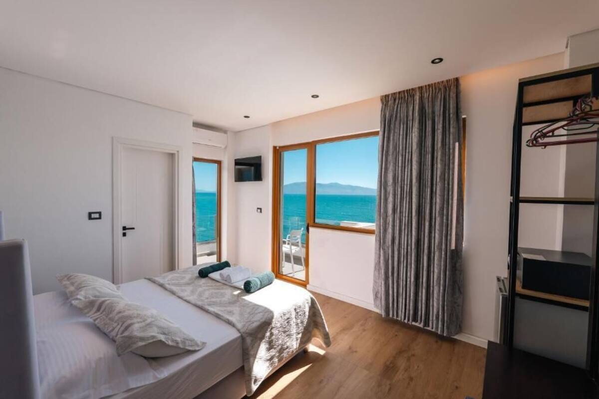 Ein Schlafzimmer mit Bett, Fernseher, Kleiderschrank und einem Balkon mit Meerblick.