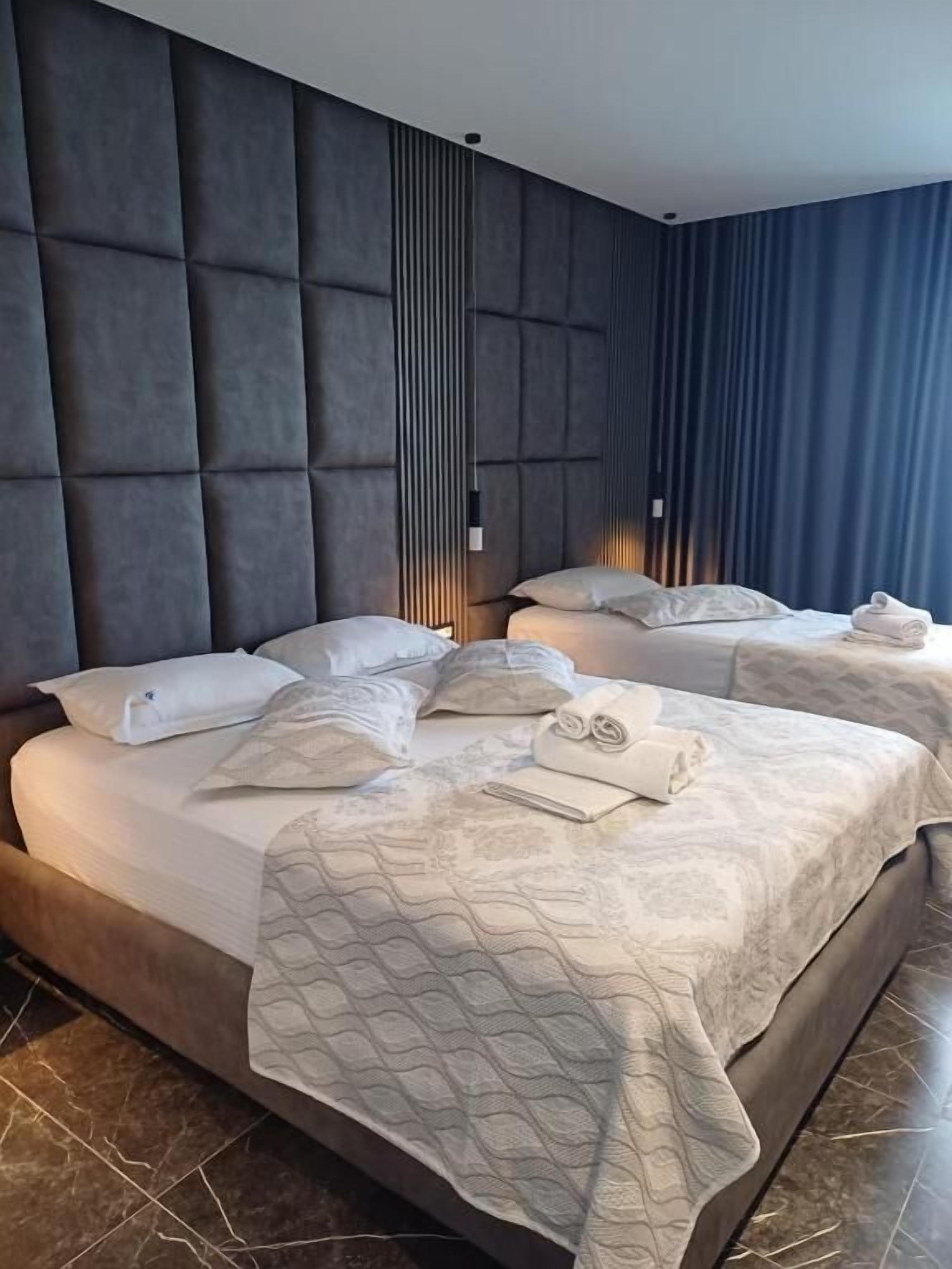 Ein modernes Hotelzimmer mit zwei Betten, einer großen, gepolsterten Kopfstütze und Blick auf die Stadt.
