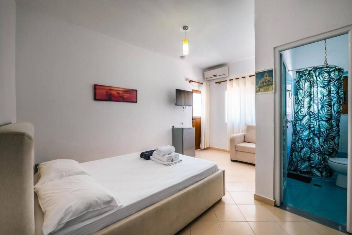 Ein Hotelzimmer mit Bett, Fernseher, Schreibtisch und einem Badezimmer mit Duschvorhang.