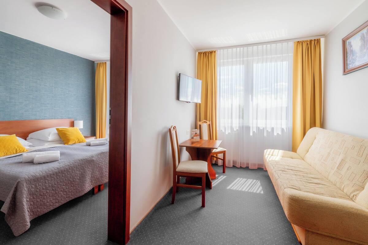 Een hotelkamer met een bed, een bank, een bureau en een televisie.