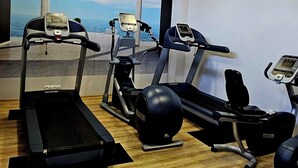 Un gimnasio con tres cintas de correr, una bicicleta estática y una máquina de remo.