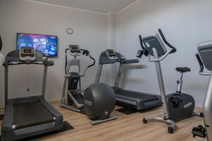 Un gimnasio con cintas de correr, elípticas y una bicicleta estática.