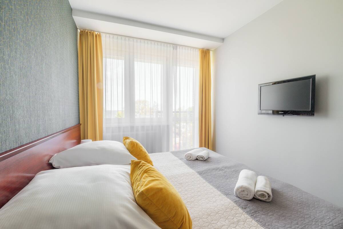 Een hotelkamer met een bed, een televisie aan de muur en een raam met gordijnen.