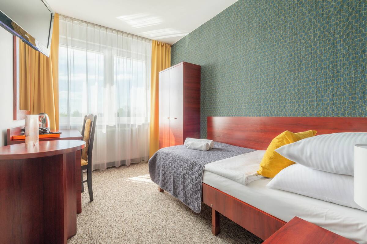 Een hotelkamer met een bed, een bureau, een stoel en een kledingkast.