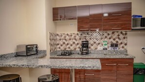 A compact kitchen with a granite countertop, a toaster, a coffee maker, and a microwave. - King One bedroom AC Hot tub elevator (Medellin)