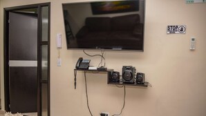 A conference room with a large flat-screen TV mounted on the wall, a telephone, and a shelf with multiple speakers. - King One bedroom AC Hot tub elevator (Medellin)