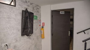 A hallway with a fire extinguisher, a door labeled 202, and a green emergency exit sign. - King One bedroom AC Hot tub elevator (Medellin)