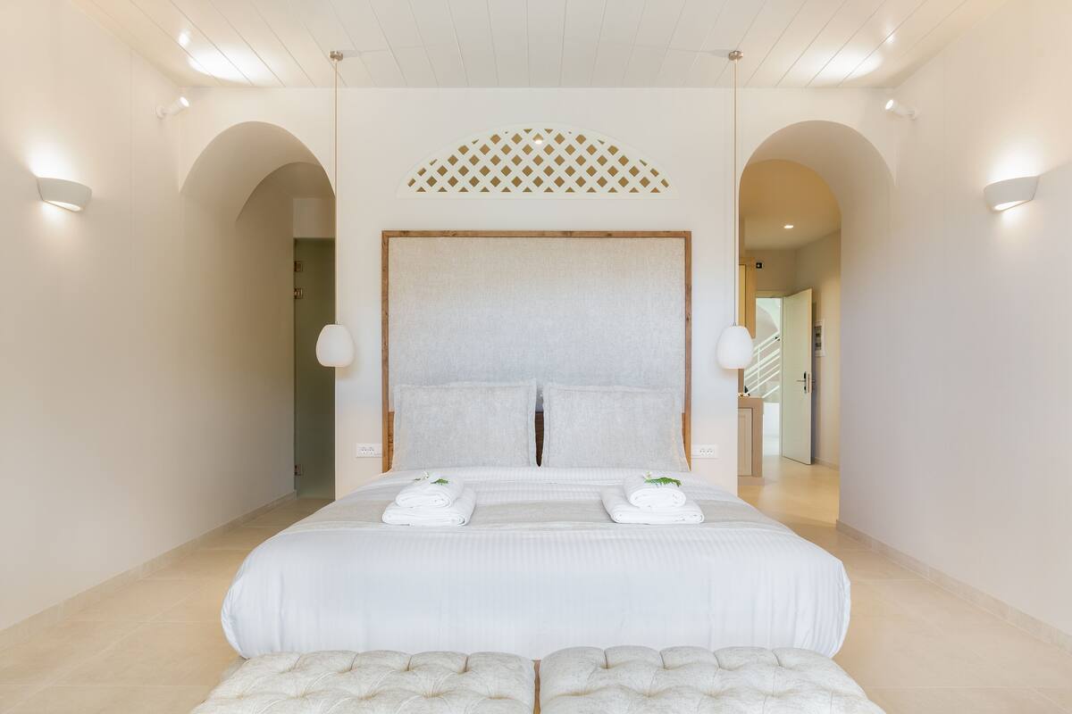 A modern hotel room with a large bed, two bedside tables, and a decorative ceiling feature.