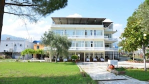 A multi-story building with a flat roof, large windows, and a covered entrance area. - Sir Motel (Edremit)