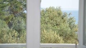 A view through a window with dense foliage and a body of water in the background. - Sir Motel (Edremit)