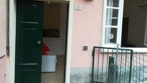 Ein pinkfarbenes Gebäude mit einer grünen Tür, einem weiß befestigten Nummernschild und einem Fenster mit weißem Rahmen.