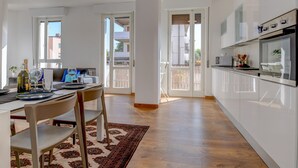 Una cucina moderna con mobili bianchi, forno integrato e zona pranzo con tavolo apparecchiato per due.