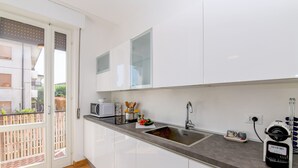 Una cucina moderna con mobili bianchi, un lavello in acciaio inossidabile e un forno a microonde integrato.