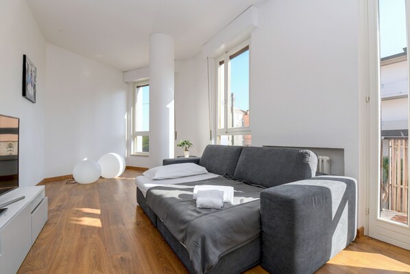 A modern living room with a grey sofa, a small white table, and a potted plant.
