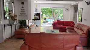Een woonkamer met een rode bank, een televisie en een groot raam.