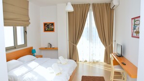 Une chambre d’hôtel avec un lit, un bureau, une télévision et une fenêtre avec des rideaux.