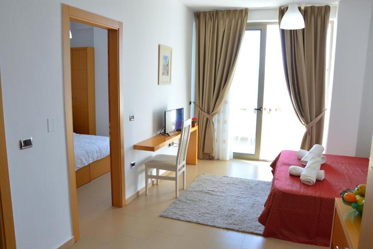 Ein Schlafzimmer mit Bett, Schreibtisch, Stuhl und einem kleinen Tisch mit Handtüchern.