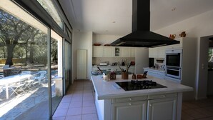 A modern kitchen with a large island, white cabinetry, and a black range hood. - House with character beetween Nimes (15km) and MontpellierHouse with character (Boissières)