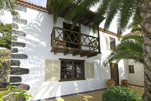 A white building with a balcony, stone steps, and a door. - Villa El Buen Jesús (Tijarafe)
