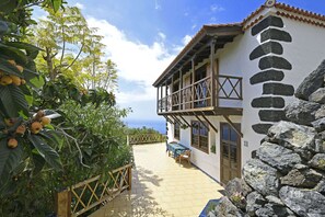 A two-story building with a balcony, a stone wall, and a view of the sea. - Villa El Buen Jesús (Tijarafe)