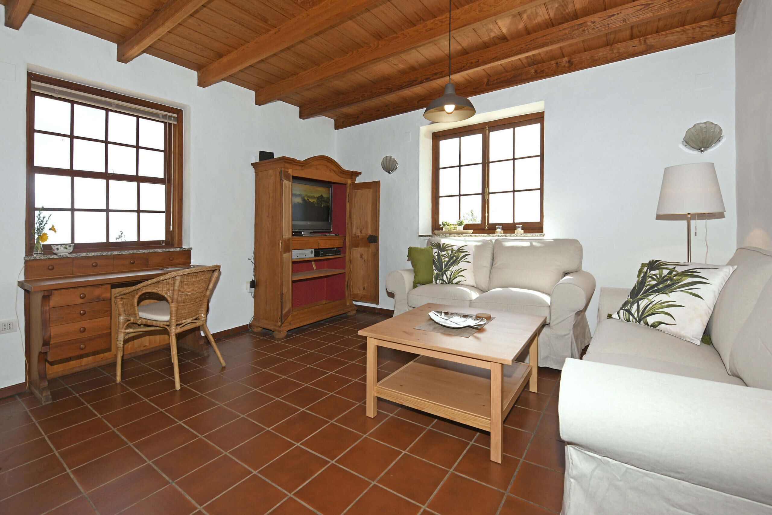 Ein Wohnzimmer mit Holzboden, einem Fernseher, einem Sofa, einem Couchtisch und einem Sessel.