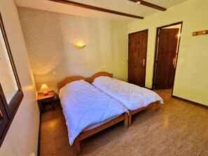 A room with a bed, a nightstand, a wall-mounted light, and two wooden doors.
