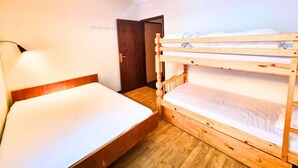 A room with a bunk bed, a single bed, a desk, and a chair. - Ground Floor Apartment for 6 - Balcony - Pets Welcome - Saint-Michel-de-Chaillol (Saint-Michel-de-Chaillol)