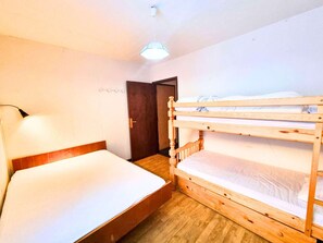 Une chambre avec un lit superposé, un lit simple, un bureau et une chaise.