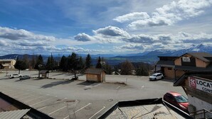 A parking lot with several cars, a small building labeled 'LE SERRE d'LAICLE', and a mountain range in the background.