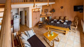 Un interno rustico in legno con una camera da letto soppalcata, una sala da pranzo e una cucina.