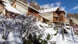 Un edificio in stile chalet con numerosi balconi, circondato da alberi innevati e un cielo sereno.