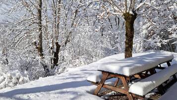 Een sneeuwbedekte picknicktafel in een bebost gebied.